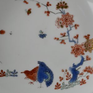 An 18th century Meissen Porcelain saucer decorated in the Kakiemon style c.1735-1745. Painted with a version of the ‘Two Quail’ design with a prunus tree and other flowers as well as insects. This Meissen porcelain saucer is quite close to the Japanese kakiemon porcelain orginal in terms of painting style as well as the enamel colours employed. However, the design has lost its asymmetry through being made more regular in form. This has resulted in the use of white space, that would have been an important element in the orginal Japanese composition, has had to give way to a design that is more evenly spread over the porcelain surface.