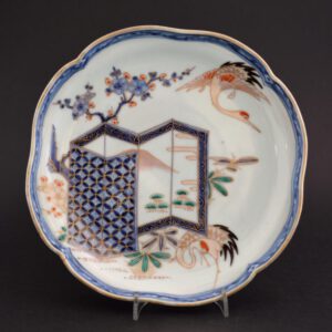 An 18th Century Japanese Porcelain Imari Dish, Arita Kilns c.1720-1740. Decorated in the Imari Palette with a Six Fold Screen with a Mountainous Scene. Bamboo and Prunus Grow Around it and their are Two Red-Crowned Cranes. The Underglaze Blue Border is of Stylised Waves. The Back is Decorated with Karakusa Scrolls and a Further Wave Border. The Base with an Apocryphal Chenghua Mark (Ming 1465 – 1487).