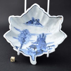 An unusual late Ming porcelain Ko-Sometsuke dish, Transition period, Tianqi 1621-1627 or Chongzhen 1628-1644. The leaf shaped form is supported by three thick column type feet and the reverse is moulded with leaf veins. The blue and white porcelain dish is painted with buildings, trees and rocks by the waters edge.