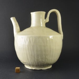 A Rare Liao Empire (907 to 1125) Stoneware Ewer from North China. This very heavy ewer with its strap-form handle and unevenly potted is typical of Liao pottery. The greyish-white stoneware is unevenly covered in a thick glaze which in certain lights has a rather yellow tone. The collar is uneven and the shoulder has a rather delicately incised pattern of stylised leaves. The body of the ewer is decorated with upright ribs that are suggestive of petals, these are deeply incised nearer the foot. The thick footrim is rather shallow, the base clearly shows the putty coloured stoneware body.SOLD Condition In excellent condition, what looks like a chip to the foot is in fact a fingerprint, this area is partially glazed. Size Height 19.8 cm (7 3/4 inches). Provenance From a Private London Collection of Early Chinese Ceramics, formed between c.1970-1990. Stock number 706 References A similar but more sophisticated Liao ewer is illustrated in : Yuegutang, A Collection of Chinese Ceramics in Berlin (Regina Krahl, G+H Verlag, Berlin, 2000) page 199, plate 155.