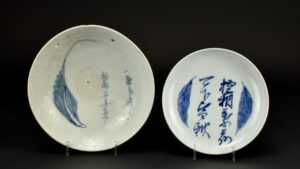 A Small Blue and White Japanese Porcelain Poem and Leaf Dish, Arita Kilns c.1690 - 1730. This thickly potted dish has a poem written in a quickly drawn cursive script, the poem is flanked by two leaves. The reverse painted with Karakusa scrolling foliage and a type of Fuku mark. This design is based on earlier Chinese and Japanese porcelain from the 17th century.