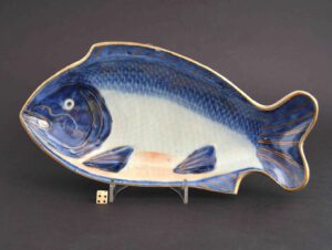 An 18th Century Japanese Porcelain dish in the form of a sea-bream c.1700-1730. The moulded form is painted in broad brush strokes of dark cobalt blue using a wet brush. The blue has settled between the scales along the paler inner edge. The lower area of the fish has a feint orange lustre wash, gilding has been employed to delineate the gills, eyes, mouth and some of the scales. The base with a Ming four character mark.SOLD Condition In excellent condition. A firing crack to the footrim. Size Length: 25.3 cm (10 inches). Provenance N/A Stock number 24190 References For a very similar Japanese Arita porcelain fish dish dated to c.1690-1730 see : Complete Catalogue of Shibata Collection (Kyushu Ceramic Museum, 2003) page 325, plate 2542. For a very similar Japanese blue and white porcelain fish dish dated to c.1690-1730 see : Complete Catalogue of Shibata Collection (Kyushu Ceramic Museum,2003) page 325, plate 2542. For a similar Japanese Porcelain dish see : The Catalogue of The Shibata Collections, The Exhibition (1) (Akihiko Shibata and Yuko Shibata and others, The Kyushu Ceramic Museum, 1990) Page 153 plate 397. For anothers Japanese porcelain dishes of this type but with gilding see our `Sold Items` 21748, 21749, 22455. For a Japanese celadon glazed porcelain fish dish dated to c.1750-1780 see our `Sold Items` number 20433.