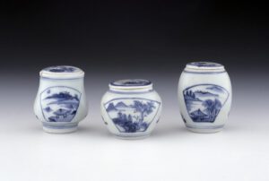 A porcelain mustard pot with flat circular cover and a notch cut out for a spoon to rest at the rim. Painted in underglaze blue in 'transitional' style with fan-shaped panels framing waterscapes with pavilions, landscapes or bamboo. The cover decorated with insects and flowering plants. The base unglazed. Found on Hatcher shipwreck. A porcelain mustard pot with a flat circular cover and a notch cut out for the spoon to rest at the rim. Painted in underglaze blue in 'transitinal' style with fan-shaped panels framing waterscapes with pavilions, landscapes or bamboo. The cover decorated with insects and flowering plants. The base unglazed. Found on Hatcher shipwreck. A porcelain mustard pot with a flat circular cover and a notch cut out for a spoon to rest at the rim. Painted in underglaze blue in 'transitional' style with fan-shaped panels framing waterscapes with pavilions, landscapes or bamboo. The cover decorated with insects and flowering plants. The base unglazed.© The Trustees of the British Museum