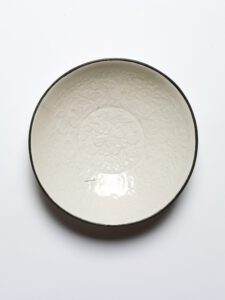 Acquired in Korea. Northern China, Ding kilns, Song dynasty, 960-1279, glazed porcelain, with moulded design and copper rim. Museum nos. 709-1883