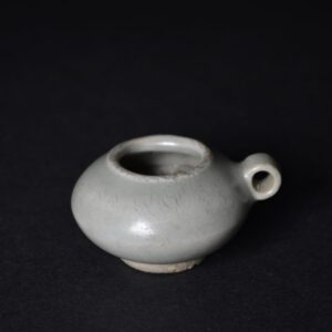 A small Song or Yuan Celadon Ware bird feeder, probably Longquan kilns, 13th or early 14th century. Of compressed circular form and unglazed base this Chinese Celadon bird feeder has a loop on the side to attach it to the interior of the bird cage. The colour is less grey and more green than appears in the photographs.SOLD Condition In excellent condition, minor feint scratches. Size Length: 4.8cm (2 inches) Provenance A Private London Collection of Early Chinese Ceramics. Lable to the base, number 304. Stock number 24950 References For a very similar Chinese celadon bird feeder, dated to the Yuan dynasty from the Eric E. Geiling Collection, Exhibited at The Cologne Museum of Oriental Art, see : Chinesische Keramik Auf Den Philippinen (Die Sammlung Eric E. Geiling, Bearbeitet Von Ulrich Wiesner, Museum Fur Ostasiatische Kunst) page 90, plate 52.