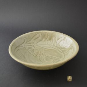 A Song Celedon Ware bowl, Fujian Province, c.12th century. Probably from the Jepara Shipwreck. The shallow celadon ware bowl is fluidly carved with flowering lotus. This carving style is mirrored in the Qingbai porcelain from the same wreck.SOLD Condition In excellent condition with almost no sign of being from a shipwreck. The glaze is exceptionally bright and shows no signs of being in a shipwreck. The glaze along the edge is slightly fritted. Size Diameter : 19 cm. (7 1/2 inches).