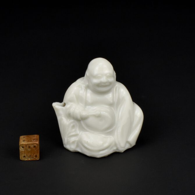 A Kangxi Blanc de Chine Porcelain Water Dropper, Dehua Kilns, Fujian Province, Kangxi period (1662-1722). This thinly potted Kangxi porcelain water dropper was made in a two-piece mould with the base pushed in by hand. The moulding is crisp for this type of object.The term `Scholar’s object` refers to something used by a Chinese scholar in his or her studio, it includes everything from scroll-tables, desks, screens, and chairs to the smaller objects found on the scholar’s desk. The material used for these desk objects varied greatly, from bamboo to stone, ivory, wood, and metal, but ceramics were by far the most commonly used material, even though ceramics rated lowest in ranking of importance. Bamboo, ivory, or wood might not be durable enough and metal was sometimes too heavy but ceramic objects could be thrown or moulded into an infinite variety of forms. Most of the objects made centred around the functions of writing and painting. Brushpots of different sizes and shape were needed to take the various types of brush, the same applies to brush rests. Water-droppers for adding water to dry solid ink when it was ground on an inkstone, as well as the inkstones themselves were all needed, as were water-pots and brush-washers. All of these could be made of porcelain. But these were not merely functional items, they conveyed symbolic mean, often enhancing scholarly virtues and the wish for longevity. They were meant to inspire the writer, poet, and artist but it is clear they could also exhibit a great sense of humour, sometimes having almost childlike quality. Objects for the scholar’s desk were made from many different ceramic bodies, during the Song Dynasty (960-1279) Qingbai porcelain was most frequently used, often in moulded forms. Blue and white porcelain objects became popular from the Ming dynasty onwards. By 17th and early 18th century, Blanc de Chine, and biscuit porcelain with coloured glazes such as green, aubergine or turquoise were also popular. Some of these objects were shipped to Europe at the time. The records of the Dashwood, a British trading vessel, were sold at in September 1703, this Supra-cargo, include 10,800 `square toys`. These were Blanc de Chine seals, I have bought and sold many of these over the years. Some are uncut, some have mould seals to the base and could have been used in China, there seals that were engraved, its likely these were not exported. However, the label, ‘square toys’, shows that in Britain they were seen as novelties to show friends and to be on display in cabinets. I’m not sure if the Chinese scholarly class would have approved. SOLD Condition In good condition, shallow chips to the edge of the spout. Size Height 5.8 cm (2 1/3 inches). Depth 3.3 cm. Provenance From a Private English Collection of Blanc de Chine Porcelain. Stock number 26369