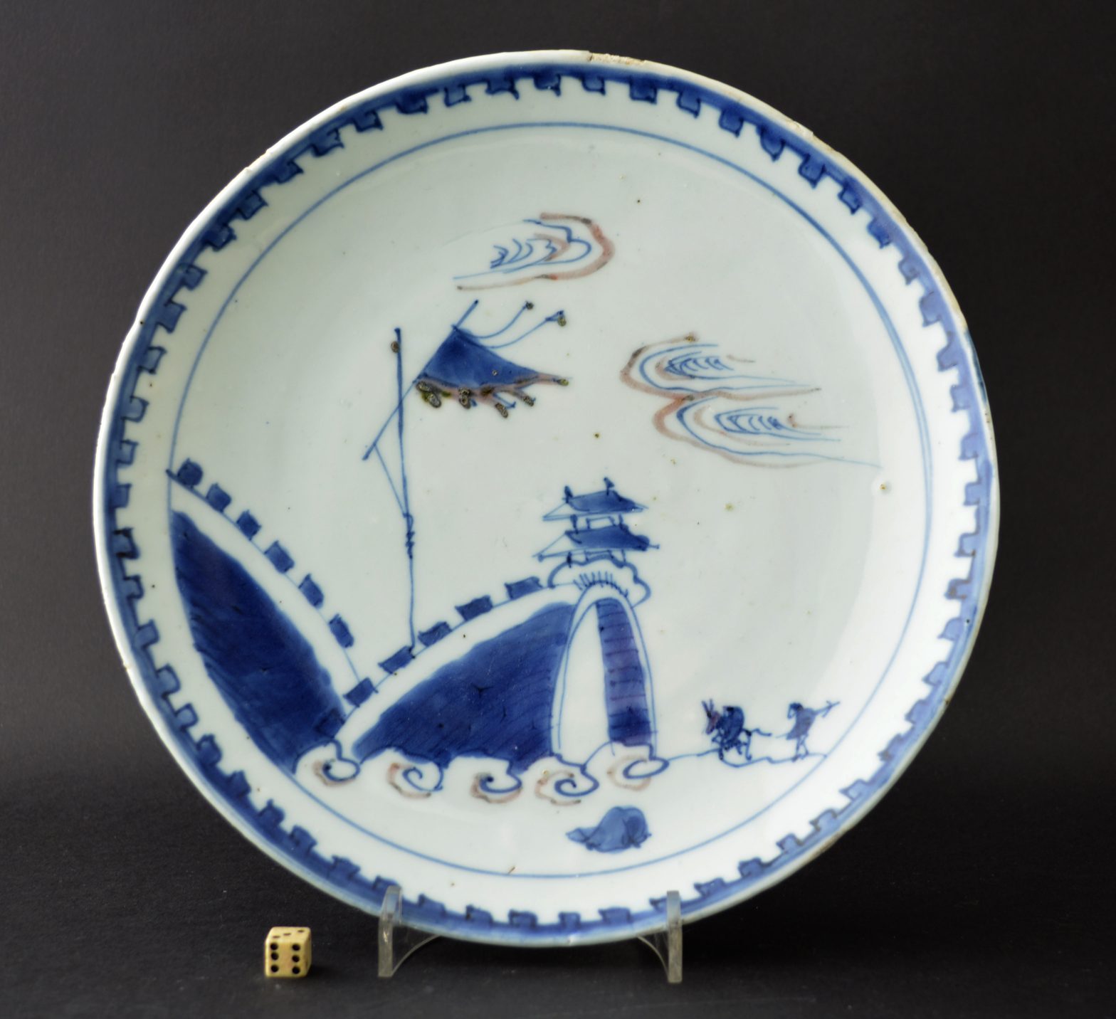 A Ming porcelain, Transitional period, Tianqi or early Chongzhen. This dish was made for the Japanese market and is decorated in underglaze cobalt-blue with touches of underglaze copper-red. The scene depicted is of a large arch in a fortified wall with a figure on horseback and his attendant in tow.SOLD Condition In excellent condition, very minor fritting. Size Diameter : 21.2 cm (8 1/4 inches) Provenance From a Private English Collection of 17th and 18th Century Chinese and Japanese Porcelain. Stock number 24967 References For a Ming porcelain dish with a very similar design in cobalt blue and copper red see : Seventeenth Century Jingdezhen Porcelain from the Shanghai Museum and the Butler Collection (Shanghi Museum,2006. ISBN 1-85759-417-7) page 56 plate 18.