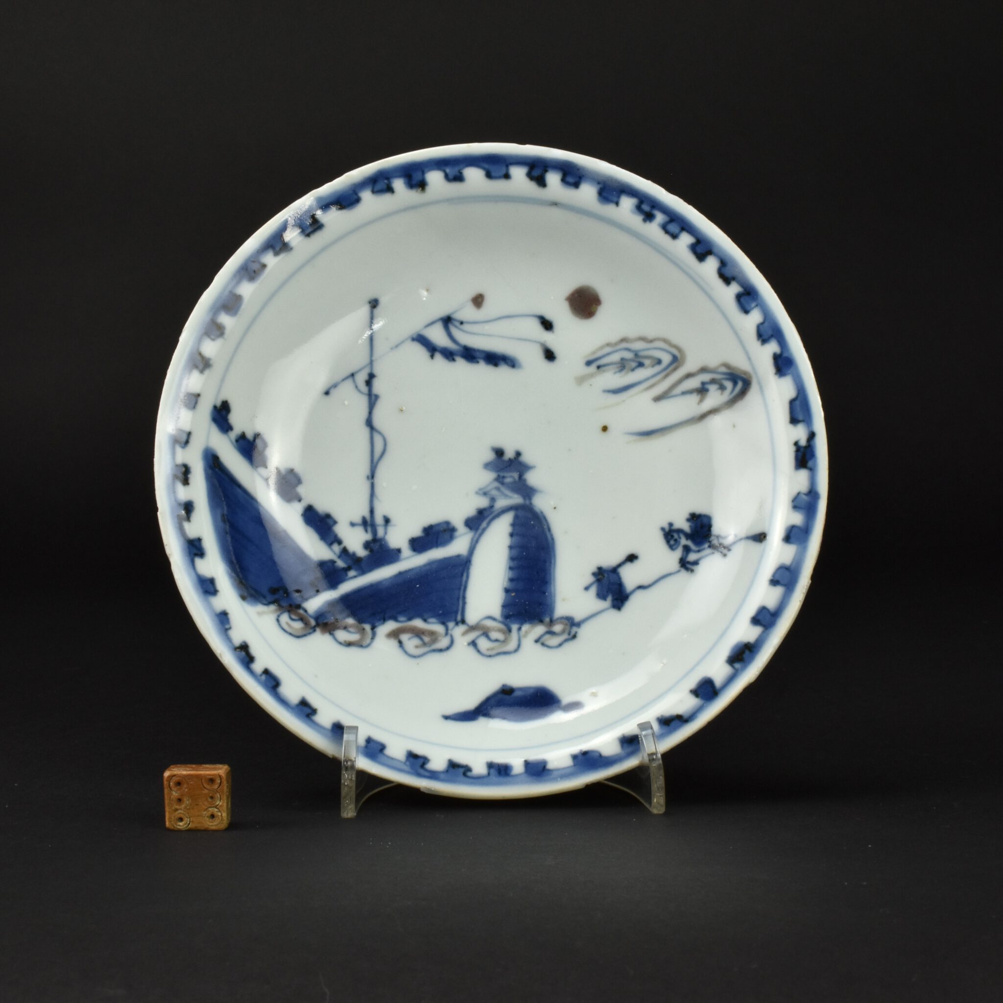 A Late Ming Ko-Sometsuke Porcelain Dish, Tianqi Period 1621 – 1627. This Kaiseki blue and white and underglaze copper red porcelain serving dish is decorated with a walled town and watch tower, a diminutive figure on horseback with his assistant are approaching the town. Ko-Sometsuke is a term used to describe Chinese blue and white porcelain made for Japan. This late Ming porcelain was made from the Wanli period (1573-1620), through the Tianqi period (1621 – 1627) ending in the Chongzhen period (1628-1644), the main period of production being the 1620’2 and 1630’s. This porcelain made in China for Japanese reflected a rise in interest of the Japanese tea ceremony but it also coincided with the beginning of porcelain production in Japan (from c.1610/20). The porcelain objects produced in China were made especially for the Japanese market, both the shapes and the designs were tailored to Japanese taste, the production process too allowed for Japanese aesthetics to be included in the finished object. Its seems firing faults were added, repaired tears in the leather-hard body were too frequent to not, in some cases, be deliberate. These imperfections as well as the fritted Mushikui (insect-nibbled) rims and kiln grit on the footrims all added to the Japanese aesthetic. These imperfections were something to be treasured by the Japanese, they reflect an imperfect world and the aesthetics of Wabi-Sabi. These ‘faults’ was an anathema to the Chinese but they went along with it to satisfy the needs of their Japanese customers. The shapes created were often expressly made for the Japanese tea ceremony, especially the meal associated with tea drinking, the Kaiseki. Small dishes for serving food at the tea ceremony are the most commonly encountered form. Designs, presumably taken from Japanese drawings sent to China, these are very varied and often extremely imaginative. They often used large amount of the white porcelain contrasting well with the asymmetry of the design, sometime the Chinese couldn’t help themselves but to fill in these gaps with ‘excess’ decoration. Many other forms were made, among them are charcoal burners, water pots, Kōgō (incense box) as well as variously shaped dishes in the form of fish, fruit or familiar country animals. SOLD Condition In very good condition, some fritting. Size Diameter : 15 cm (5 3/4 inches) Provenance N/A Stock number 26312 References For Tianqi dishes with a version of this design which includes the use of copper red see : The Peony Pavilion Collection: Chinese Tea Ceramics For Japan' Christie's, London, 12th June 1989. Lot 344.